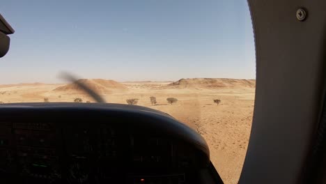 apuntando a una brecha entre dos grandes dunas en namibia mientras volaba a baja altura en un avión pequeño