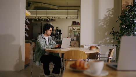 young man working on a laptop in a coffee shop