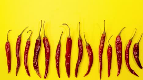 Chiles-Rojos-De-árbol-Detienen-El-Movimiento-De-Movimiento-En-Fila-Sobre-Un-Divertido-Fondo-Amarillo-Vibrante