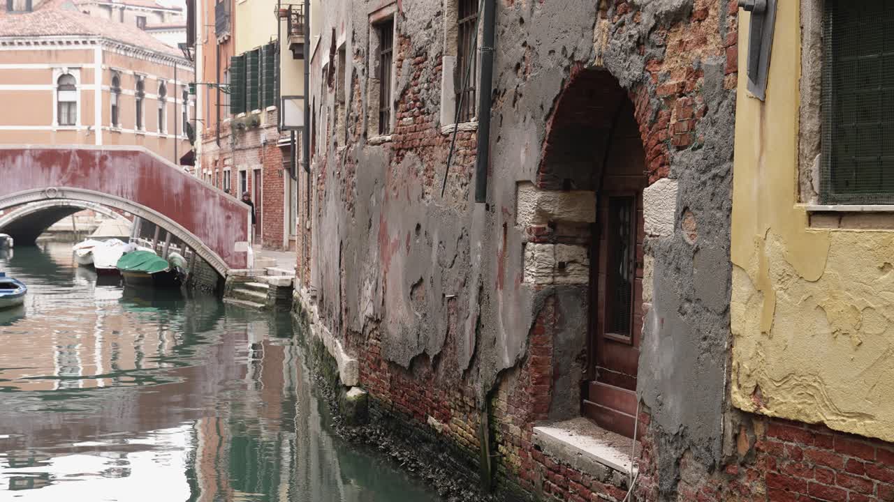Worn down weathered doorway opens to venice italy canal and bridge, static