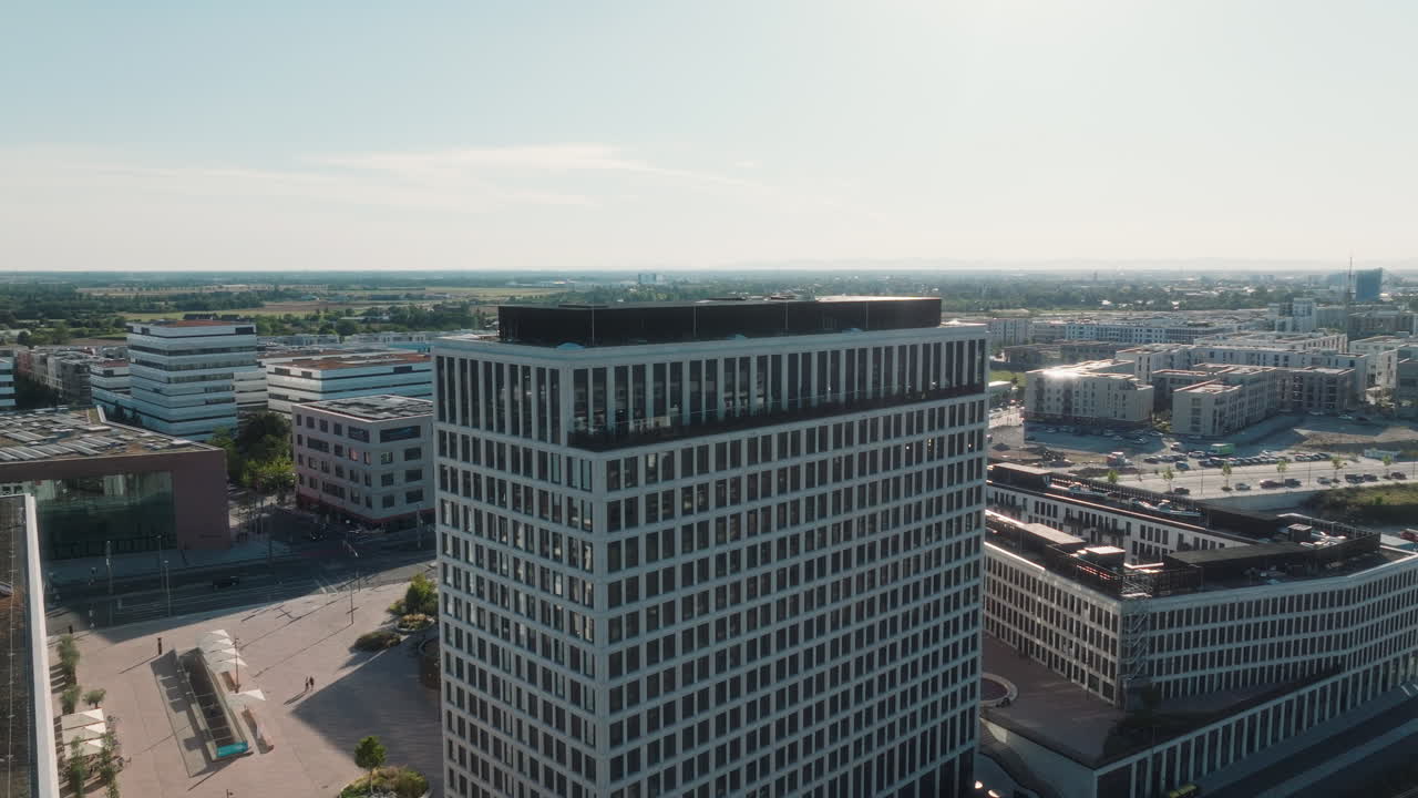 Drone orbiting around the Atlantic Hotel, starting over the plaza and moving behind the tower. Sunlight reflects on the glass as the railway tracks, a train at the platform and the city appear