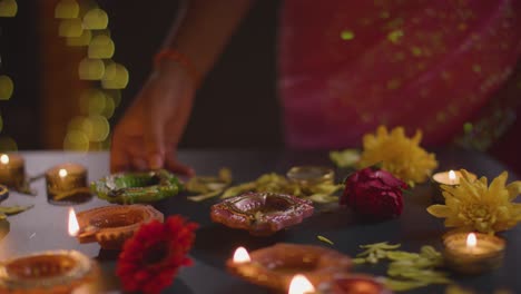 close-up de uma mulher acendendo lâmpadas a óleo diya comemorando o festival de diwali 1