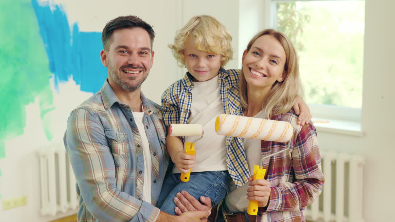 행복한 가족은 그들의 집을 칠합니다.