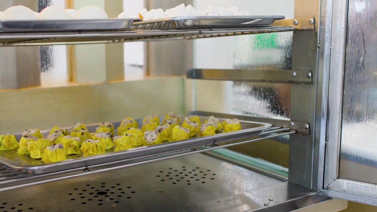 Person som öppnar ångskåp för att servera färska Shumai-dumplings