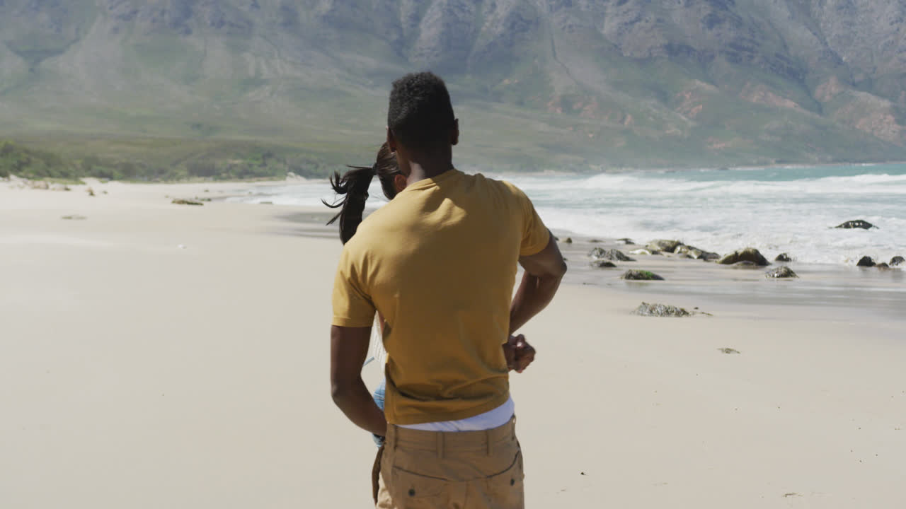 feliz pareja afroamericana bailando juntos en la playa