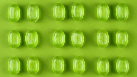 green mint mentol lollipops, candies, bonbons disappear on purple background. summer bright texture studio shot for store, supermarket, close up top view. children favorite sweets made of sugar.