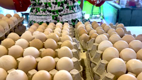 vendor arranging eggs at a bustling market stall