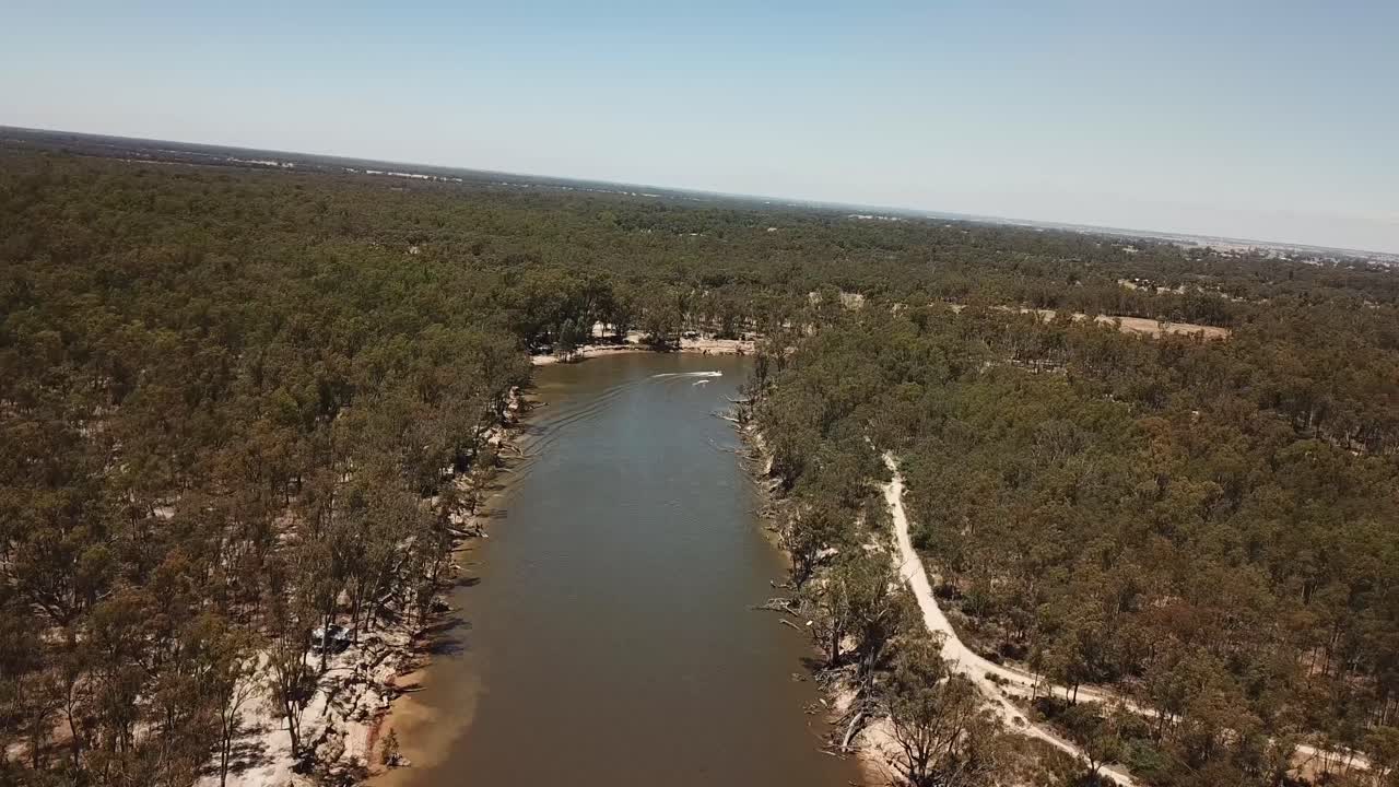 Vista aerea con drone su un fiume fangoso in Australia, con campeggio e una barca lenta che passa