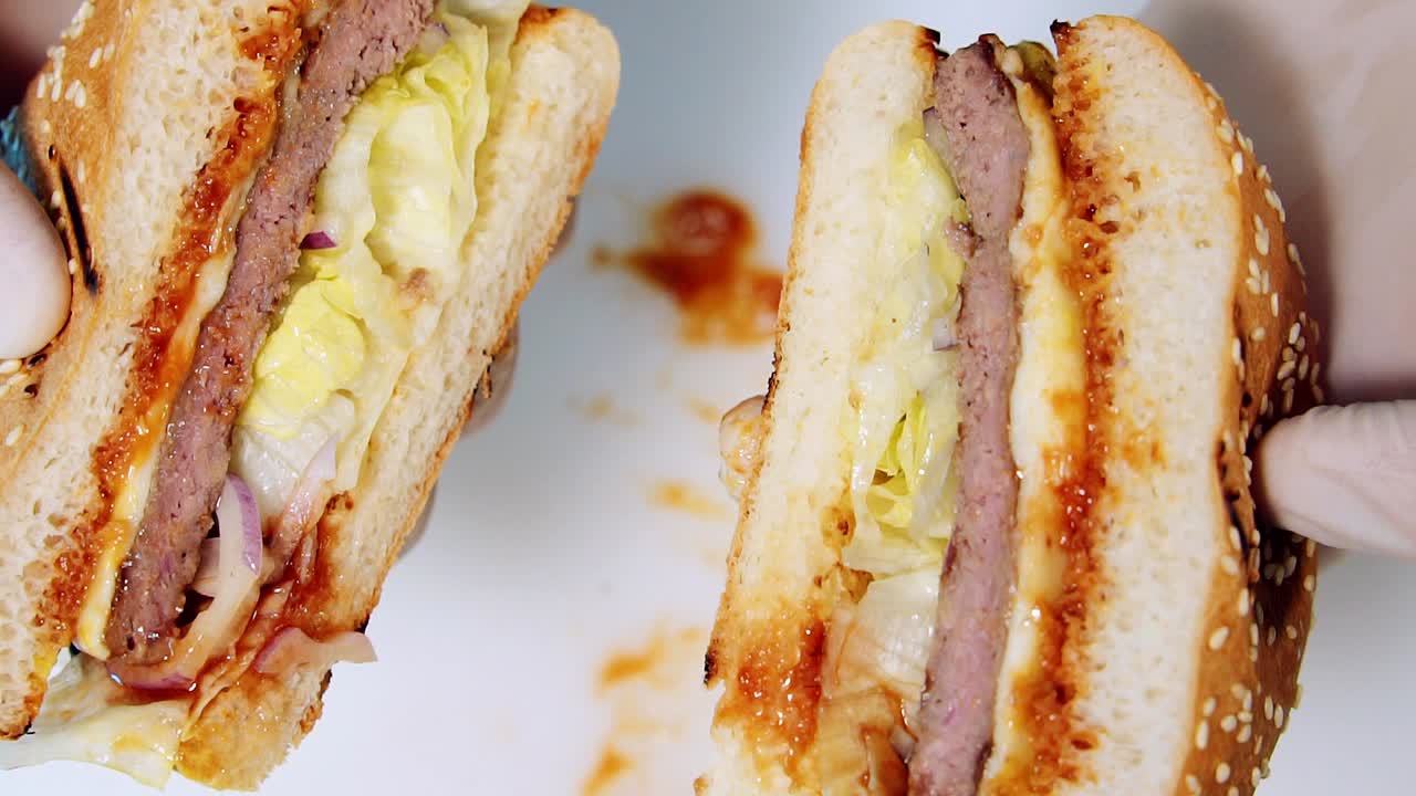 Fresh delicious burger. Chef shows juicy hamburger cutted into halves with appetizing filling. Ready burger in cook's hands. Close-up