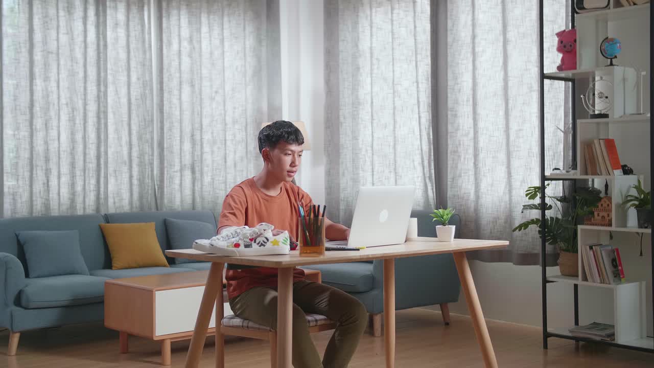 아시안 소년 신발 디자이너가 집에서 노트북으로 디자인하고 있습니다.
