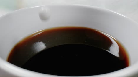 creamer is poured into a cup of coffee