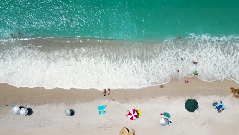 Drone-Aéreo-Panorámico-De-Una-Hermosa-Playa-Con-Gente-Jugando-En-El-Agua-Y-Relajándose-En-La-Orilla