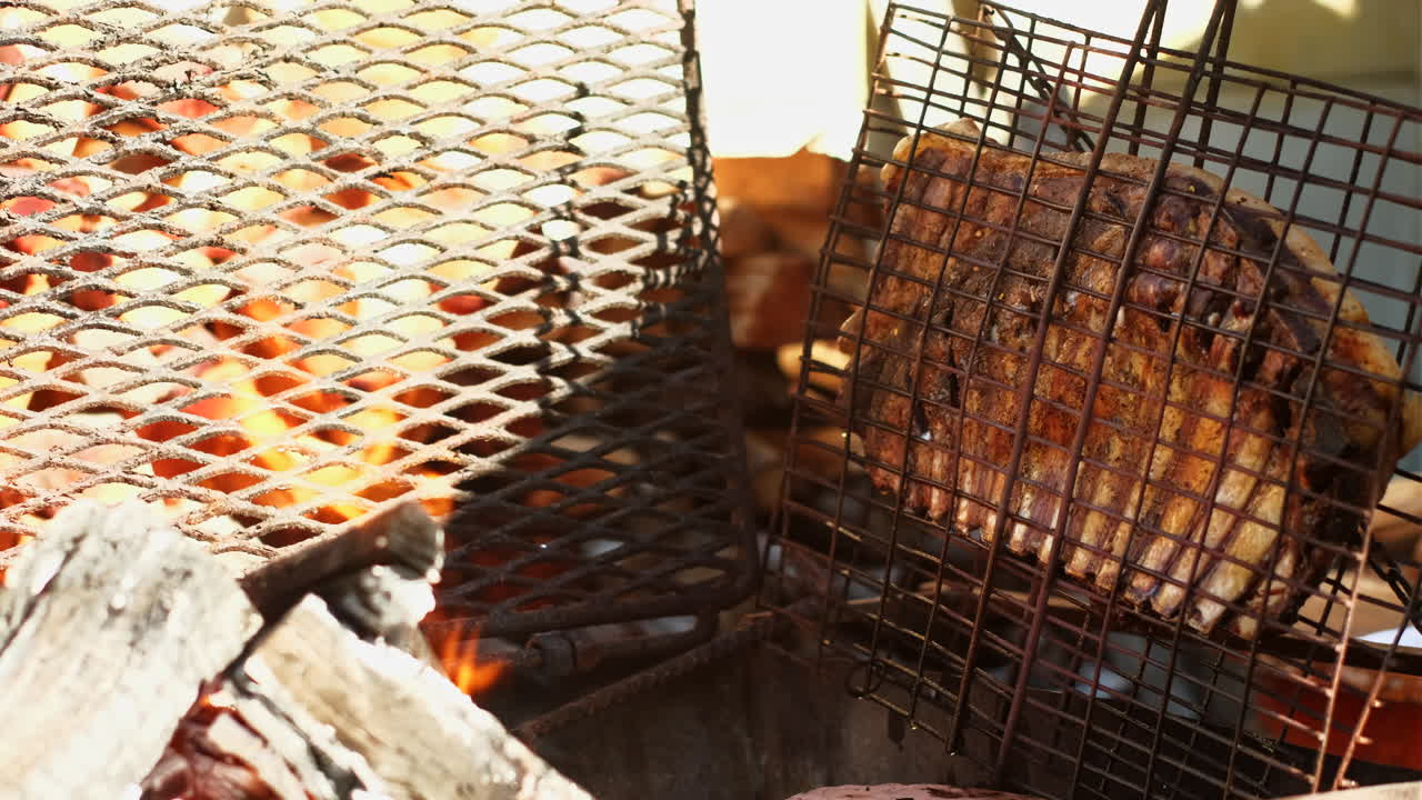 Standing lamb rib being grilled on side of hot wood fire, South African culture