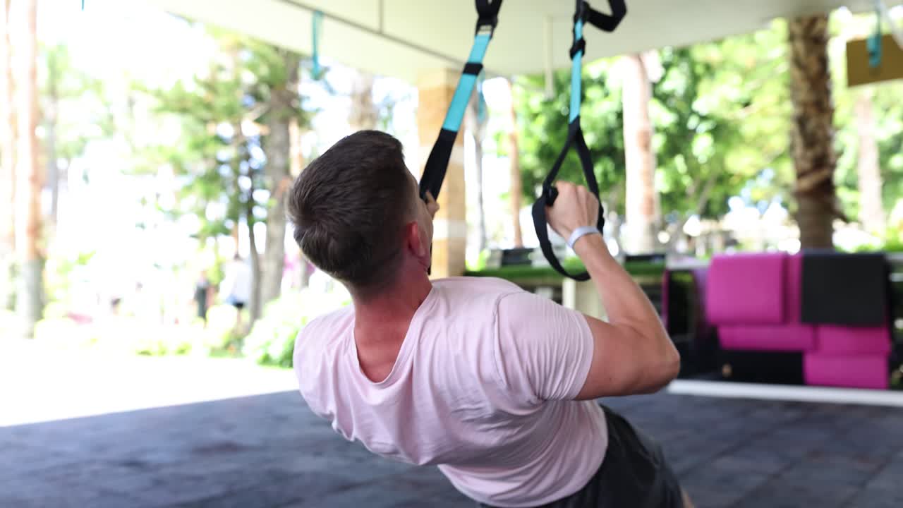 Man doing TRX suspension training exercise outdoors