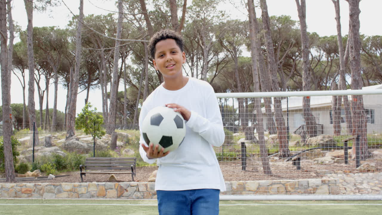Boy holding soccer ball on field, looking determined during outdoor practice, copy space