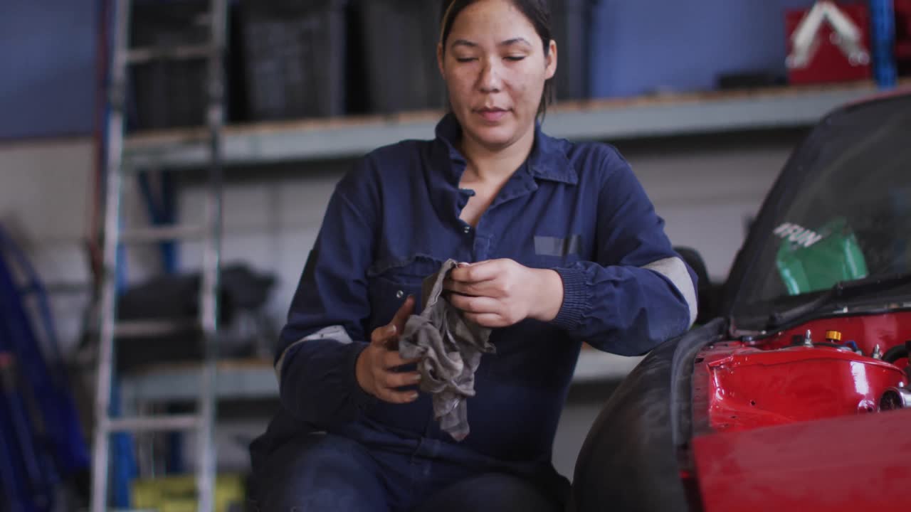 retrato de una mecánica limpiando sus manos con un paño sentada en una estación de servicio de coches