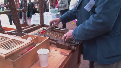 Old-carpenter-work-in-workshop-weave-wicker-net-in-to-chair-with-tiny-hamer-and-wedge