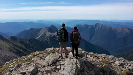 two hikers on a mountain summit with a vast landscape view