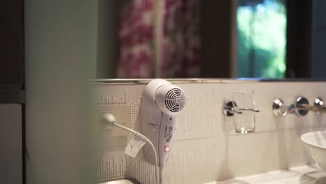 close up of a hotel bathroom countertop featuring a wall mounted hairdryer, contemporary fixtures, and a mirror, highlighting the clean and modern design