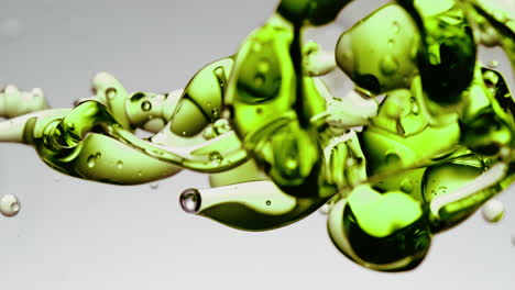 transparent green oil bubbles and fluid shapes in purified water on a white gradient background