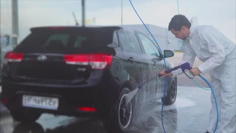 man washing a black car at a self-service car wash
