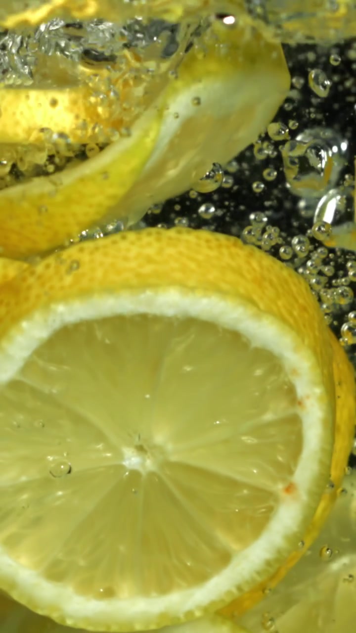 Fette di limone fresche che si tuffano nell'acqua con bolle