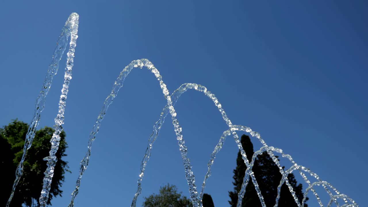 Fountain with water jets falling on center in city park at summer day.