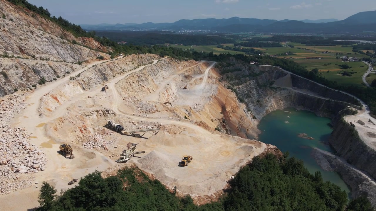 Aerial footage captures the expansive Savinjska quarry in Slovenia, revealing layered rock faces, heavy machinery at work, and striking landscape contrast.