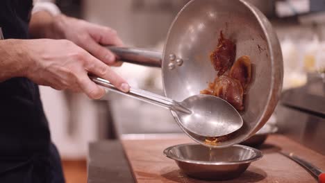 Male-cook-holds-the-meat-in-the-frying-pan-with-a-silver-spoon-so-the-fat-can-drip-from-the-tub