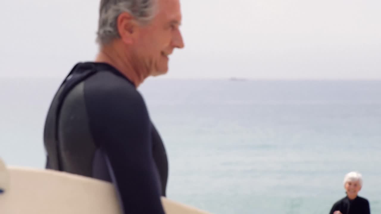 Retired couple holding surfboards