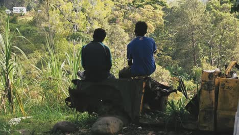 Two-male-sitting-on-an-old-damage-car-starring-into-the-mountains-and-valley