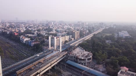 cinematic aerial shot revealing newly built cable styled majerhat bridge road in the center of kolkata, metro station building construction close to majerhat railway station and cityscape