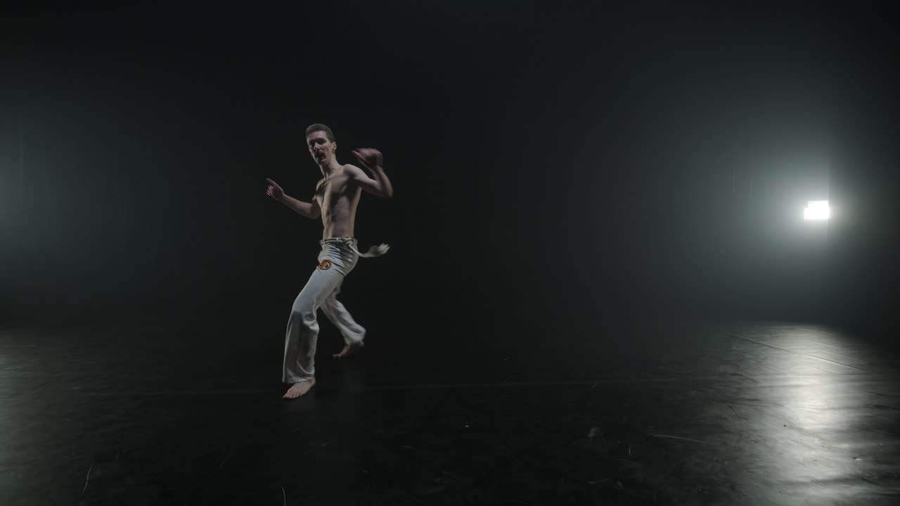 Lottatori di Capoeira che eseguono mosse dinamiche sul palco. Arti marziali, danza e acrobazie in azione. Atleti a torso nudo che mostrano forza, flessibilità e tecnica sotto i riflettori