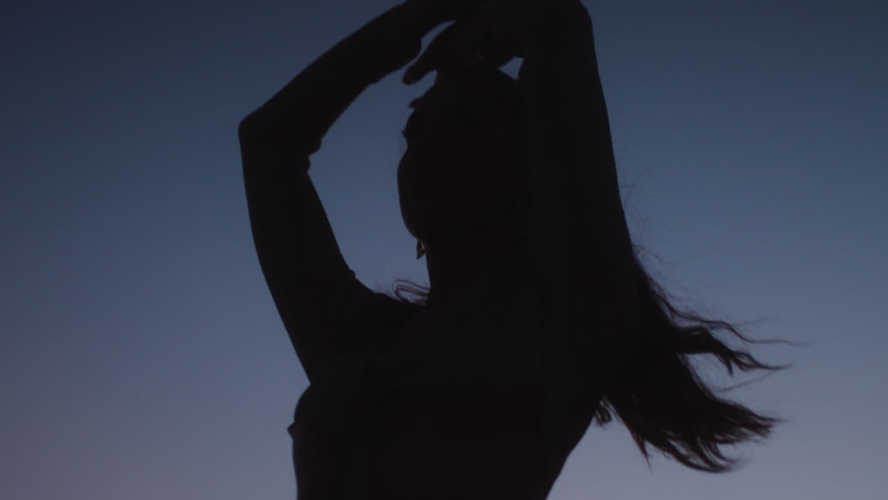 Silhouette cinematografica di una donna nel deserto in piedi sulla cima di una duna al tramonto