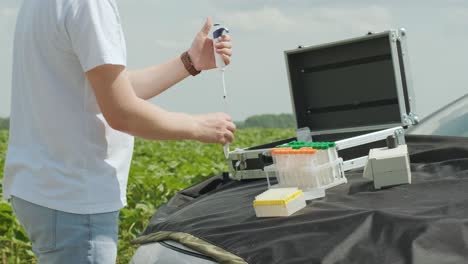 laboratory worker holding professional glassware and testing plant sprouts before harvest in the field.