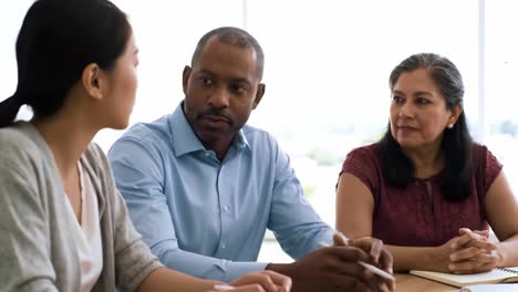 three professionals engage in a discussion about project updates in a bright office. the diverse team shares ideas and strategies, fostering collaboration and teamwork.