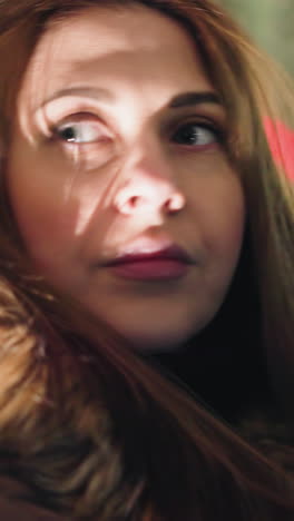 First-person view of a woman in a winter coat with a fur hood, inside a car at night without her head warmer. She is looking out thoughtfully,blurry city lights