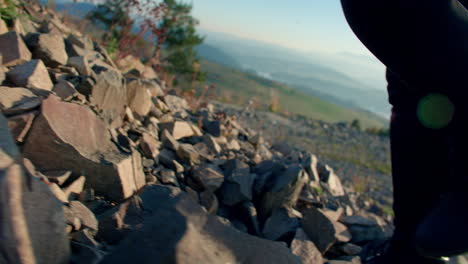 Mädchen-Klettert-In-Schwarzen-Wanderschuhen-Auf-Einem-Felsigen-Hügel-Mit-Weitläufiger-Außenlandschaft-Im-Hintergrund