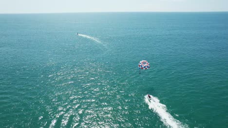 Aerial-images-of-the-beach-on-a-sunny-day,-following-water-parachute,-Aerial-drone-images,-Beach-Jaco,-Puntarenas,-Costa-Rica,Dolly-Inn