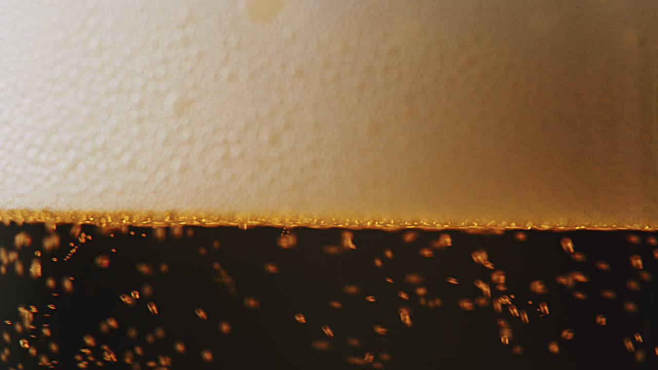 un primerísimo plano de espuma de cerveza llenando un vaso limpio