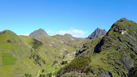 valley of mountain ranges with forestry slopes and clouds sailing by, aerial drone view