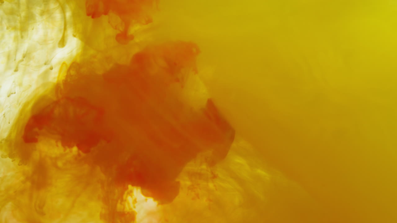 노란색과 오렌지색 페인트 또는 염료가 색 배경에 물에 떨어지면 회전하는 다채로운 연기 배경을 만니다.