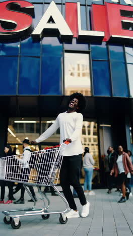 joyful man jumps with shopping cart outside a store with a large 'sale' sign