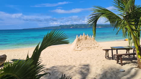 Puka-Beach-on-Boracay-Island,-Philippines,-Sand-Castle-and-Table-on-White-Sand-Behind-Green-Tropical-Trees