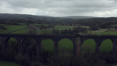 An-aerial-view-of-the-a-large-Buxton-railway-bridge-viaduct-in-the-Derbyshire-Peak-District-national-park,-a-busy-train-track-in-the-beautiful-Derbyshire-countryside,-Aerial-photography