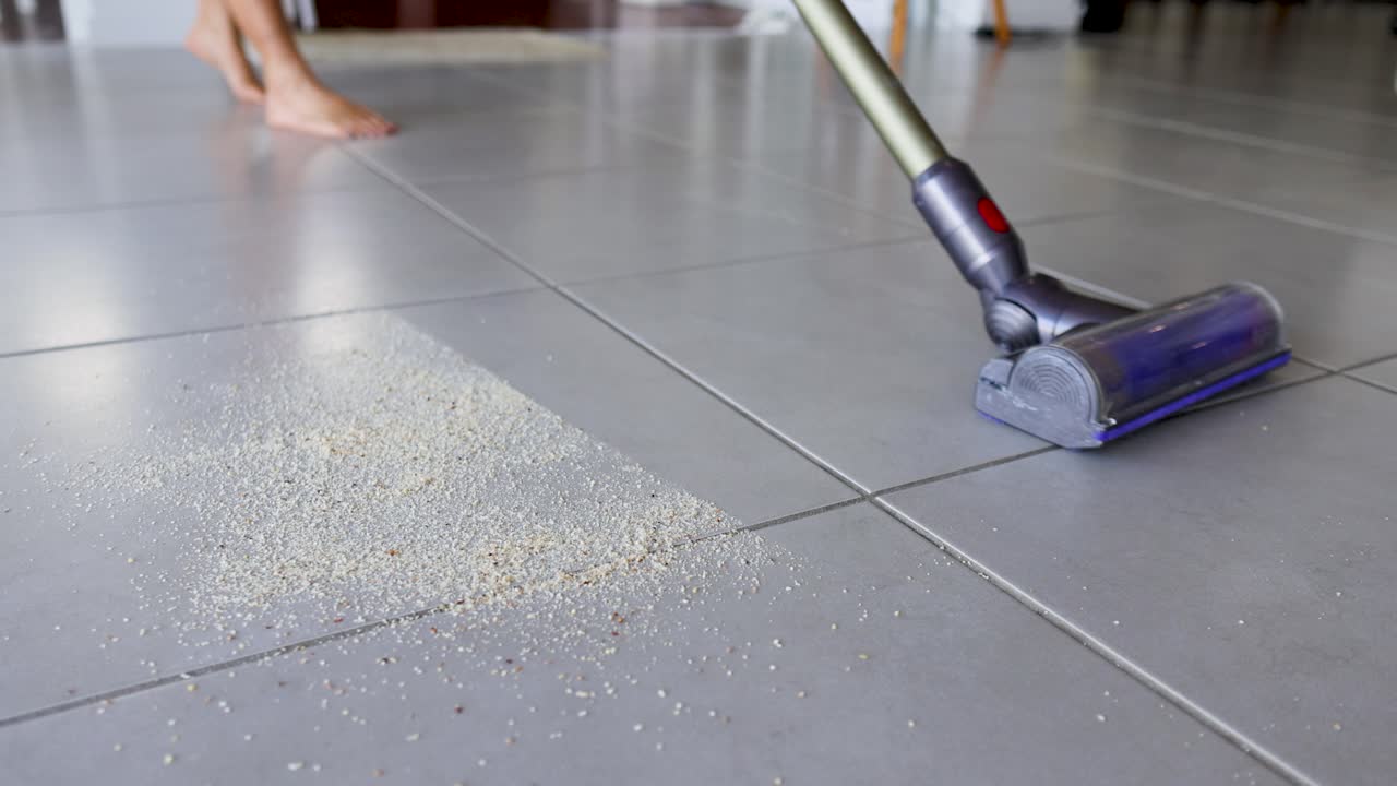 A vacuum cleaner efficiently removes crumbs from a tiled kitchen floor, highlighting cleanliness and modern home care