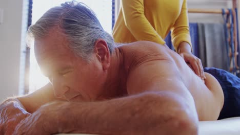 fisioterapeuta dando masaje de espalda a un hombre mayor 4k
