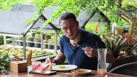 hombre comiendo almuerzo en un restaurante de jardín tropical