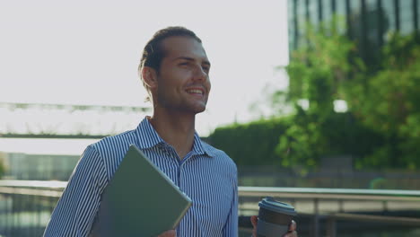 happy businessman walking outdoors with a tablet and coffee cup