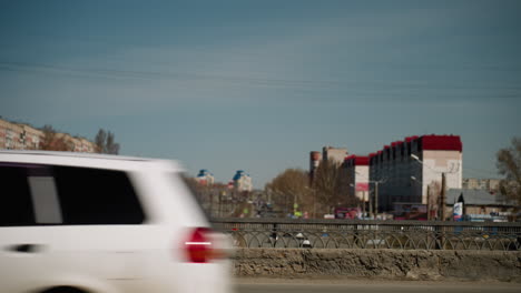 close view of an urban cityscape featuring distant buildings and a busy road with moving vehicles on the bridge and under the bridge